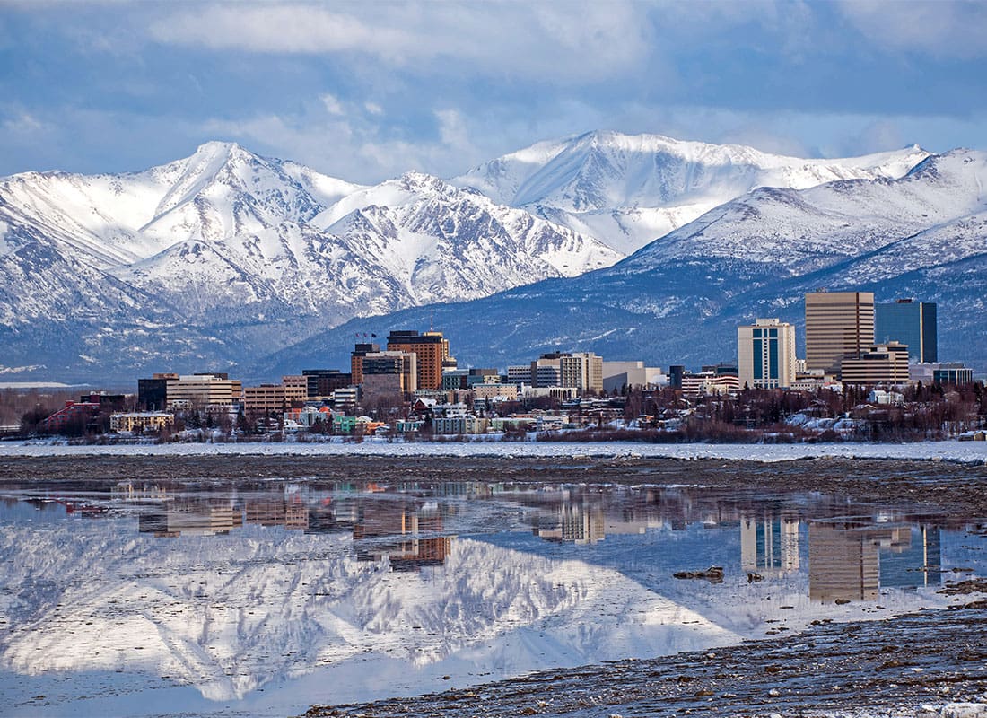 Anchorage, AK - View of Buildings in Downtown Anchorage Alaska with Snow Covered Mountains in the Background